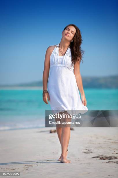 entspannte junge frau zu fuß am tropischen strand - weißes kleid stock-fotos und bilder
