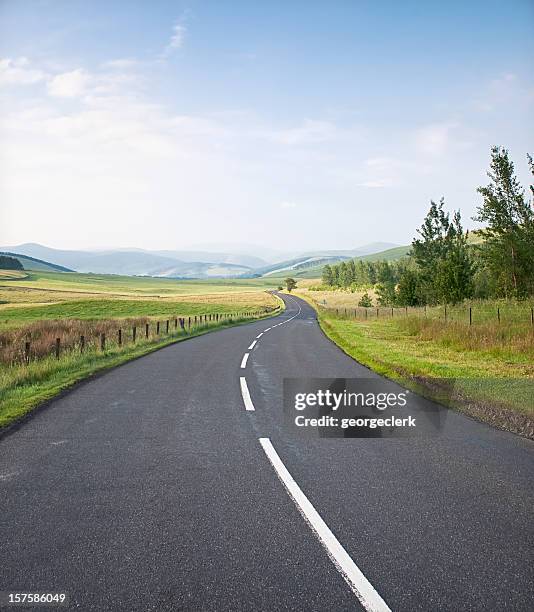kurvige country road - karge landschaft stock-fotos und bilder