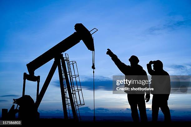 oil workers inspecting a pump jack - wellhead stock pictures, royalty-free photos & images