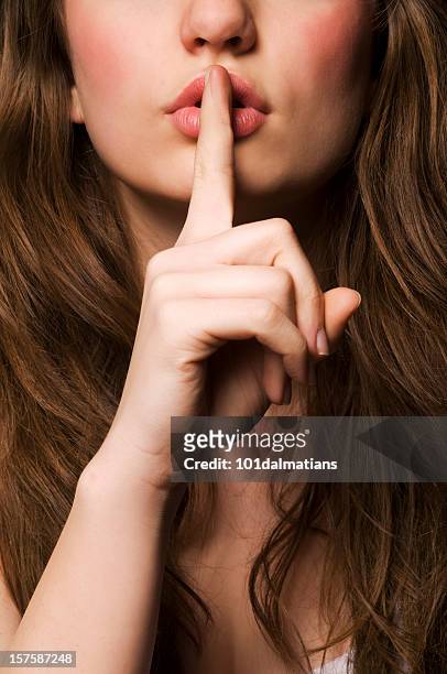a woman putting her fingers to her lips in silence - mysterious blond woman stock pictures, royalty-free photos & images