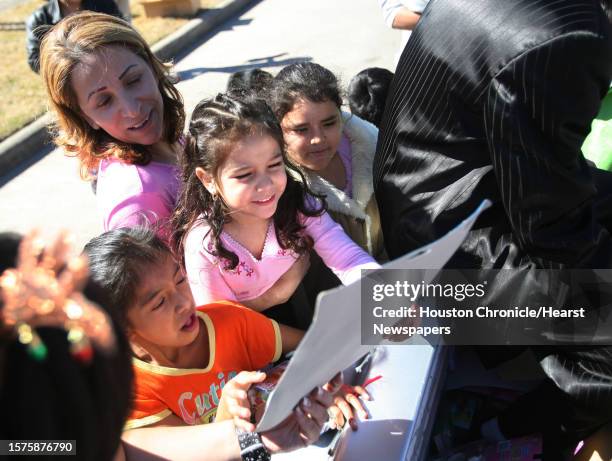 Katy Solano holds her daughter Juliana Maldonado as she receives a gift from Richard Reyes, aka Pancho Claus, during the 14th Annual Juguetes Para el...