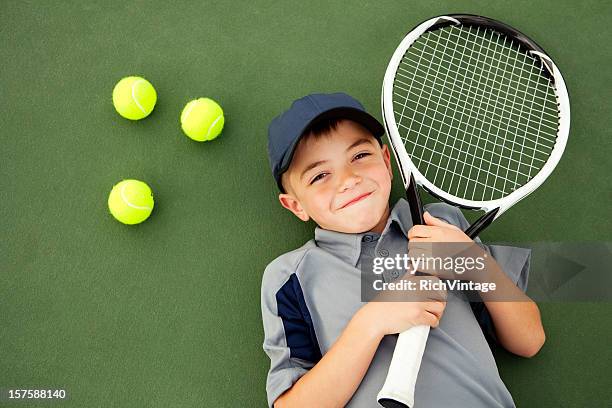 young boy and tennis player lying down on tennis court - tennis boy stock pictures, royalty-free photos & images