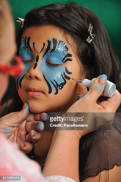 girl getting her face painted - geschminkt gezicht stockfoto's en -beelden