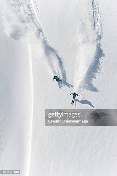 aerial view of two skiers skiing downhill in powder snow - mountain snow skiing stock pictures, royalty-free photos & images