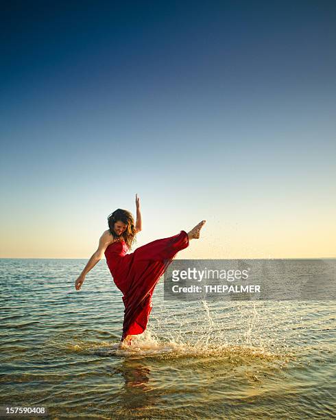 teenager kicking high with her foot in the beach - woman long dress beach stock pictures, royalty-free photos & images