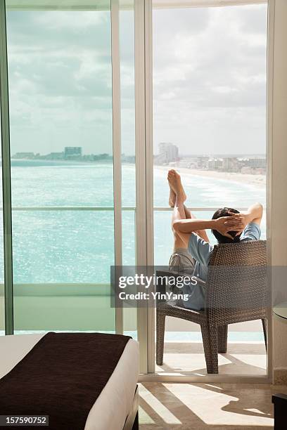 relaxing man on hotel room balcony enjoying sea beach view - beach balcony stock pictures, royalty-free photos & images