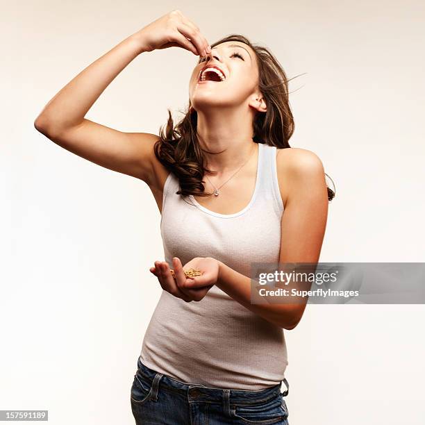 healthy eating. young woman eating nuts. square format. - seed stock pictures, royalty-free photos & images