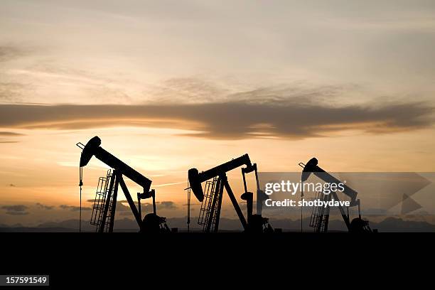 three pumpjacks and a yellow sky - mining exploration stock pictures, royalty-free photos & images