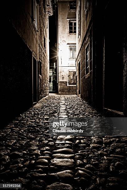 lonely cobblestoned dark alley - dark alley stock pictures, royalty-free photos & images