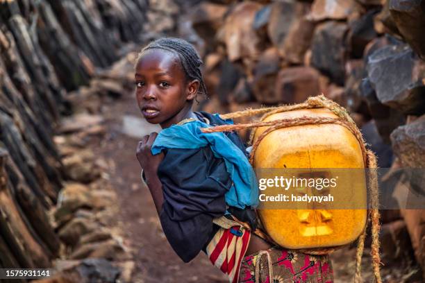 afrikanisches mädchen, das wasser aus dem brunnen trägt, äthiopien, afrika - african girl drinking water stock-fotos und bilder