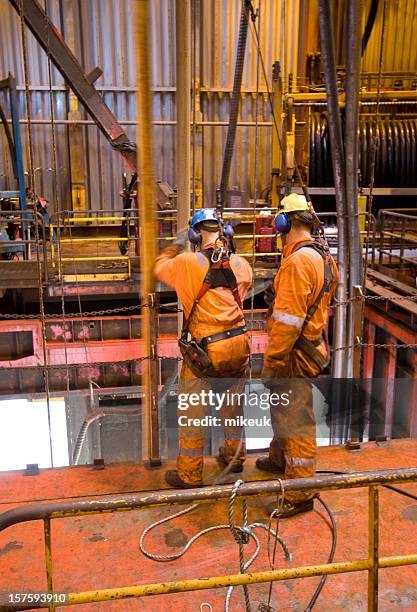 two men in orange working on an oil rig - oliewerker stockfoto's en -beelden