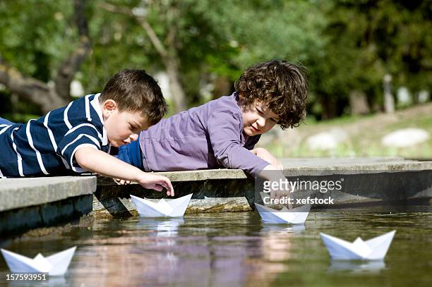 Playing paper. Мальчик с корабликом. Ребенок с бумажным корабликом. Дети пускают бумажные кораблики. Ребенок запускает бумажный кораблик.
