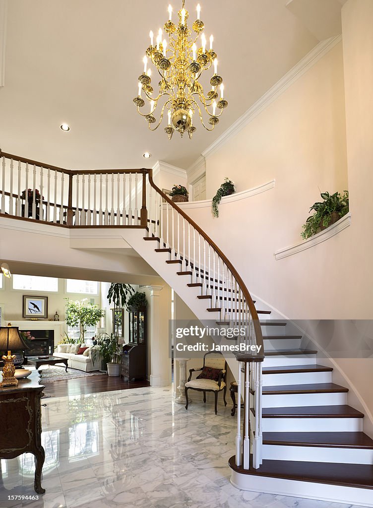 Escalera blanca de gran vestíbulo, piso de mármol reflejan hogar, con Chandelier