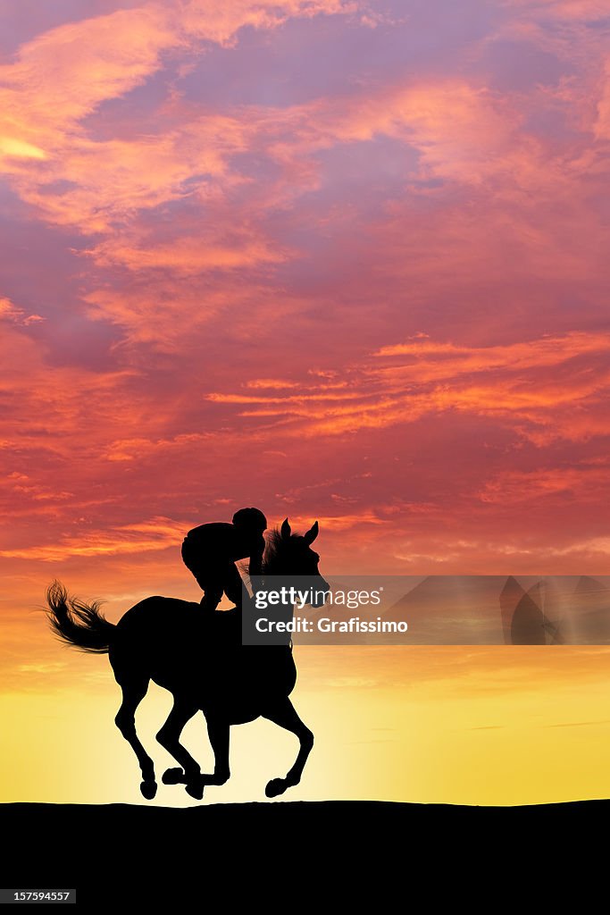 Jockey riding a racehorse at sunset