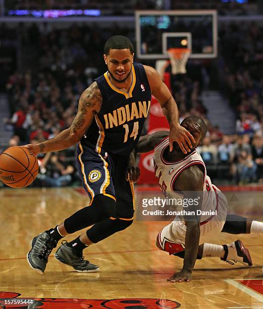 Augustin of the Indiana Pacers fouls Nate Robinson of the Chicago Bulls as he tries to drive to the lane at the United Center on December 4, 2012 in...