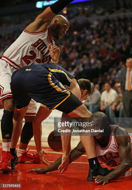 Tyler Hansbrough of the Indiana Pacers losses control of the ball under pressure from Taj Gibson and Nate Robinson of the Chicago Bulls as he tries...
