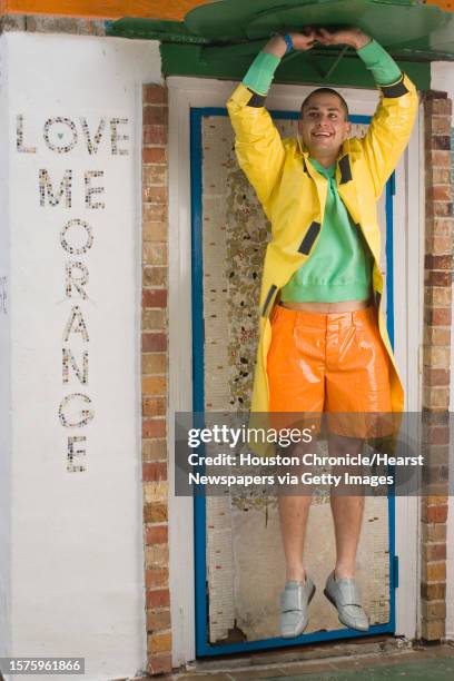 Scott Kondziela of Page Parkes Models wears Prada orange vinyl shorts, yellow vinyl rain slicker and grey vinyl shoes, Lacoste green cotton V-neck...