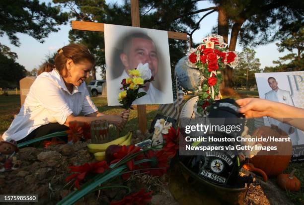 Maria de los Angeles Villegas places flowers and sister Michelle Villegas places the Houston Fire Fighter helmet on her brother's alter while her...