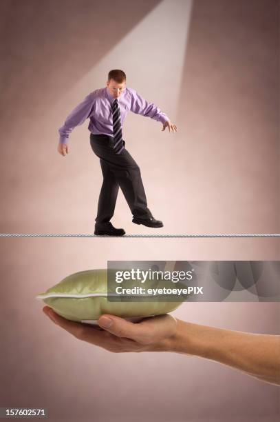 businessman on tightrope with safety below - protection luxe stockfoto's en -beelden