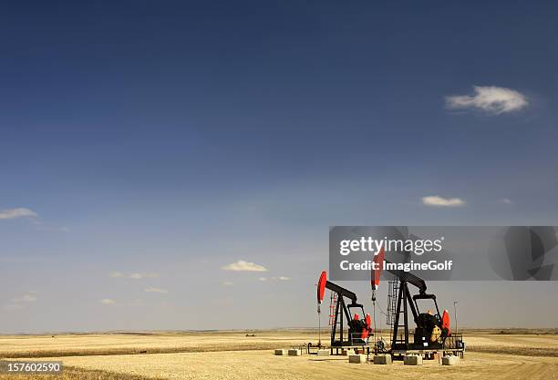 two red pumpjacks in north dakota oil field - pump jack stock pictures, royalty-free photos & images