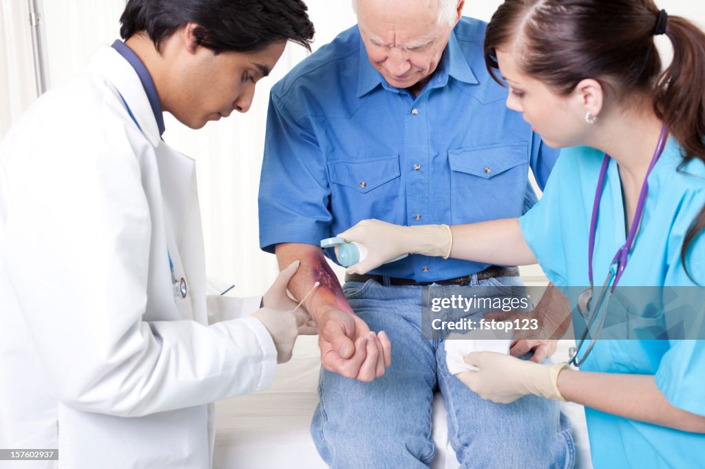 Doctor, nurse treating man's wound, burn. Emergency room hospital.