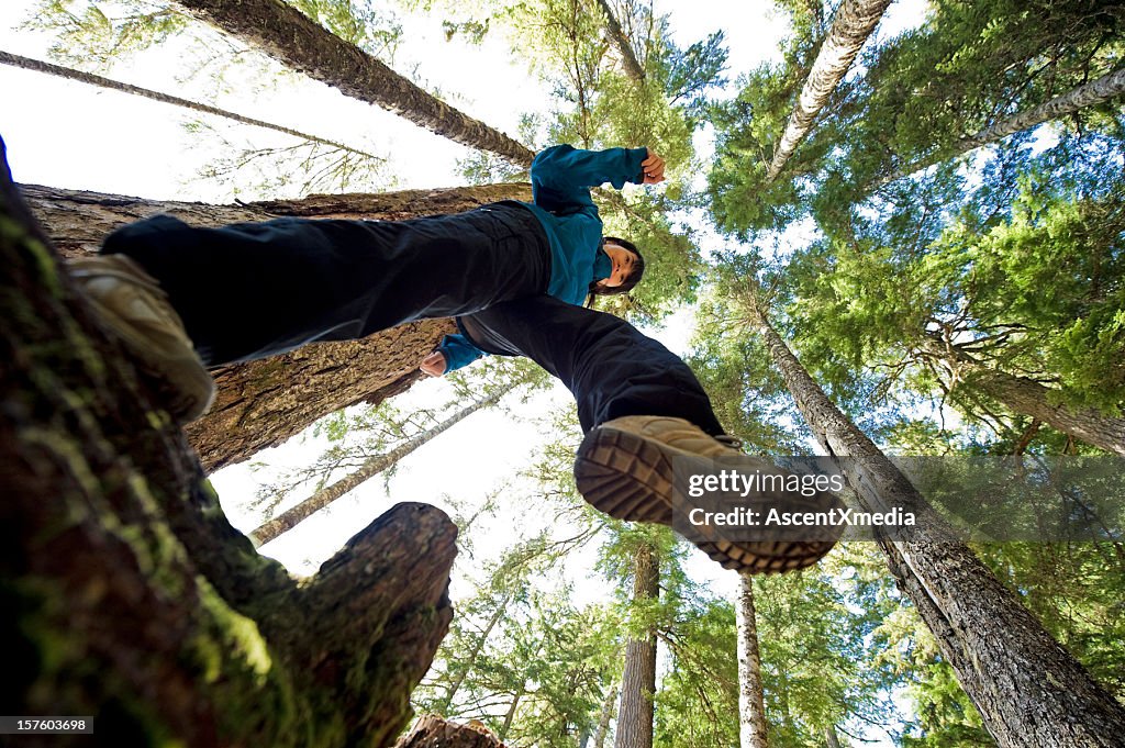 A worms eye view of a hiker with a view of the tall trees