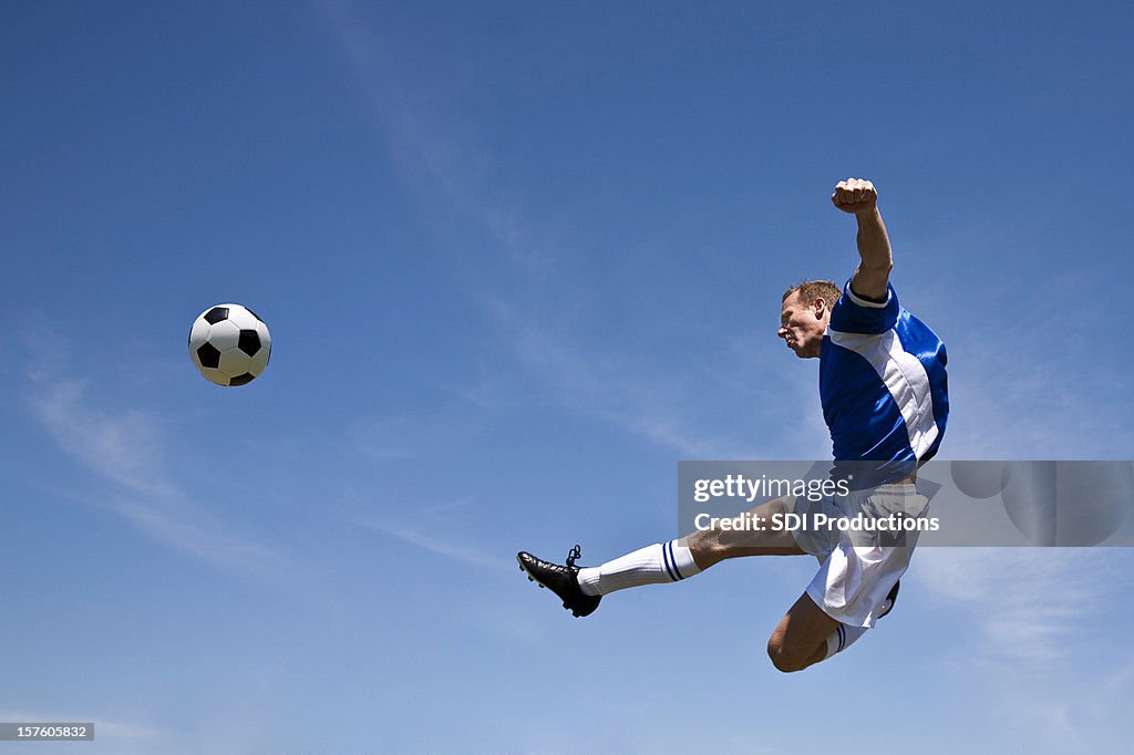 Jogador de futebol chutando a bola ao ar
