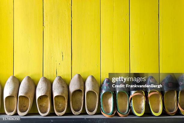 row of wooden shoes against a yellow wall - clogs stock pictures, royalty-free photos & images