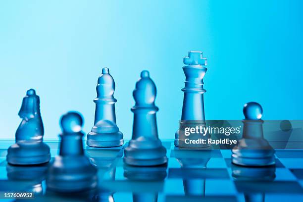 glass chessmen shine against a blue background - chess pieces stock pictures, royalty-free photos & images