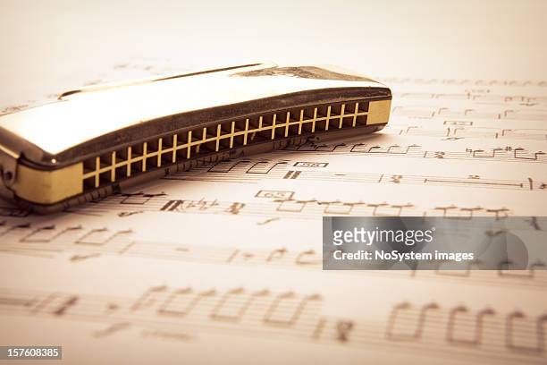 a harmonica on a sheet of music - harmonica stock pictures, royalty-free photos & images