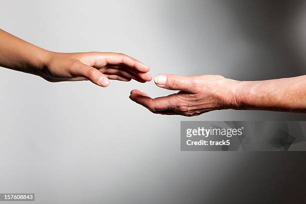 hands: young and old hands reaching out to each other - releasing stock pictures, royalty-free photos & images