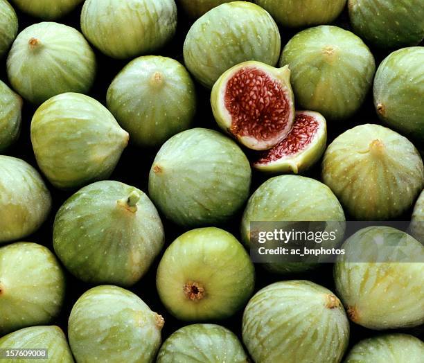 pile of fresh green figs, one cut open - vijg stockfoto's en -beelden
