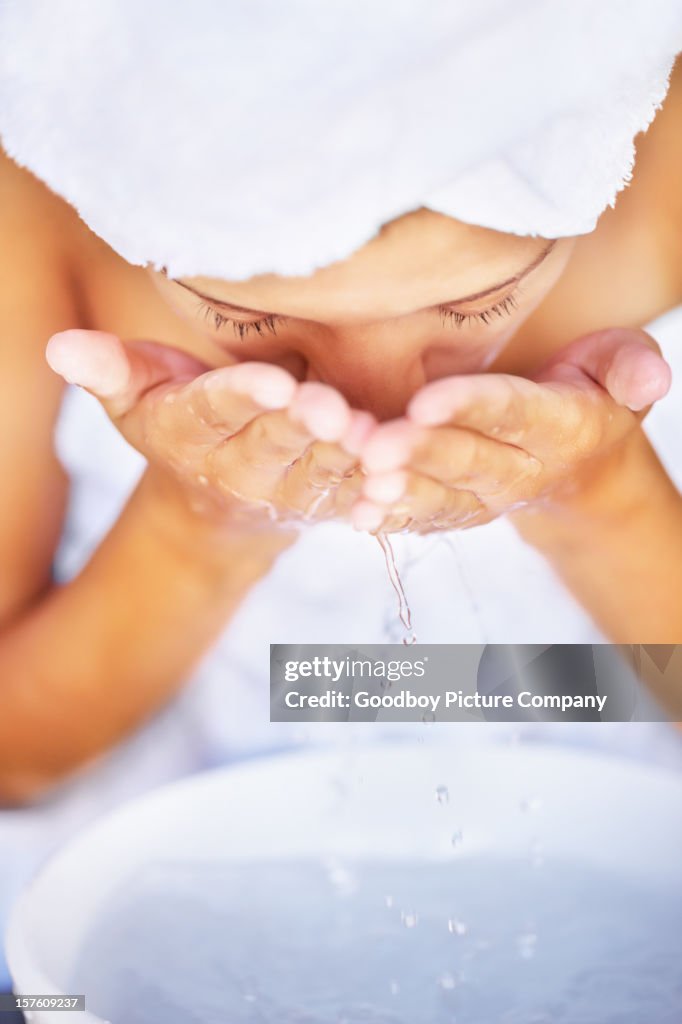 Young female washing face at a sink