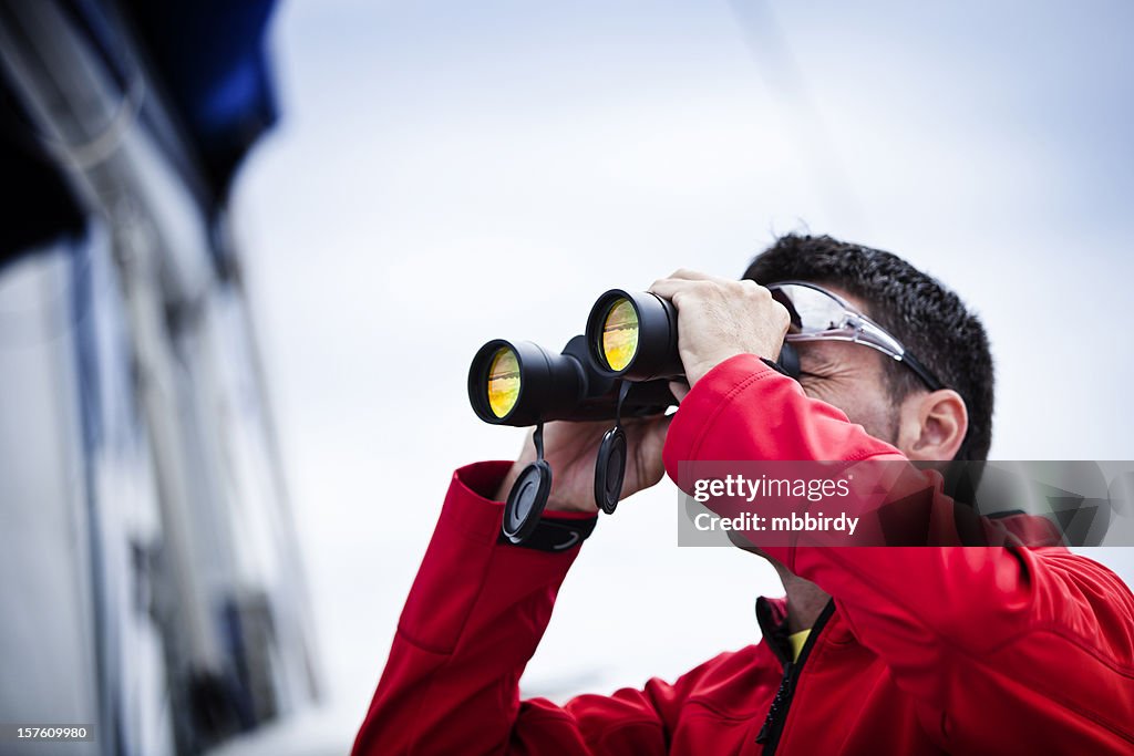 Sailor with binoculars on sailboat