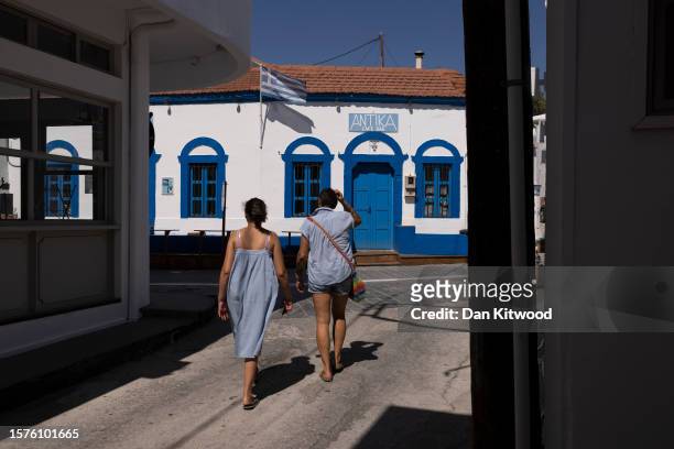 People walk down a street on July 28, 2023 in Gennadi, Greece. While the town of Gennadi wasn't directly affected by fire damage, the smoke and...