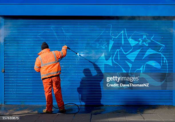 washing graffiti off a security grill. - removal men stockfoto's en -beelden