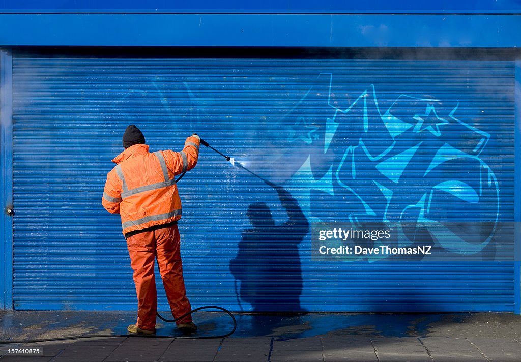 Washing graffiti off a security grill.