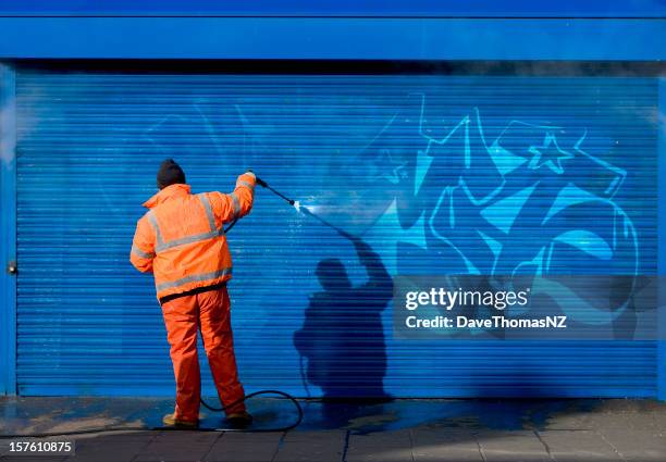 washing graffiti off a security grill. - street art stock pictures, royalty-free photos & images