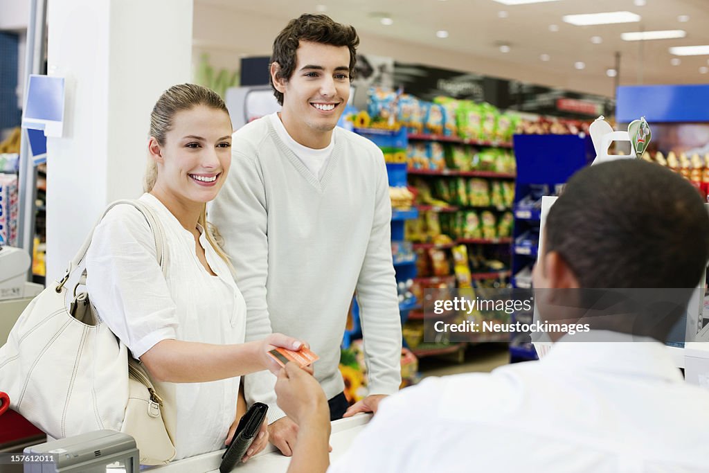 Woman handing credit card to cashier for payment
