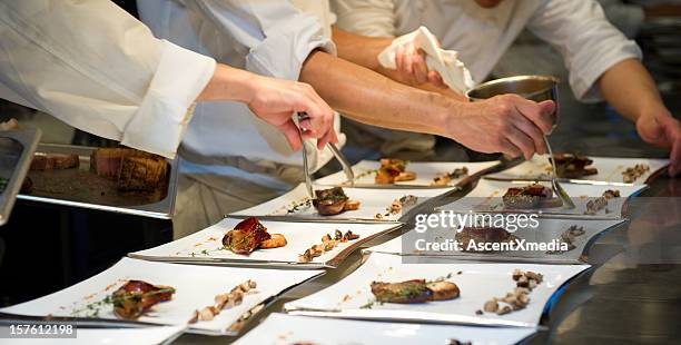 kitchen staff and chef preparing gourmet meals for a party - banquet stockfoto's en -beelden
