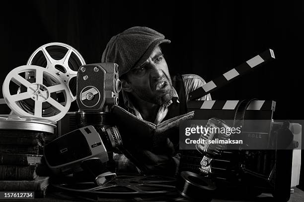 actor with hat scowling and practicing screenplay - 8mm film projector stock pictures, royalty-free photos & images