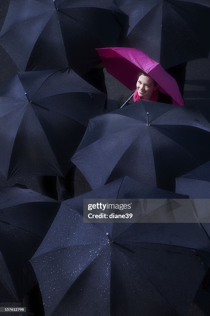 Mujer mirando hacia arriba en sol romper a través de la lluvia