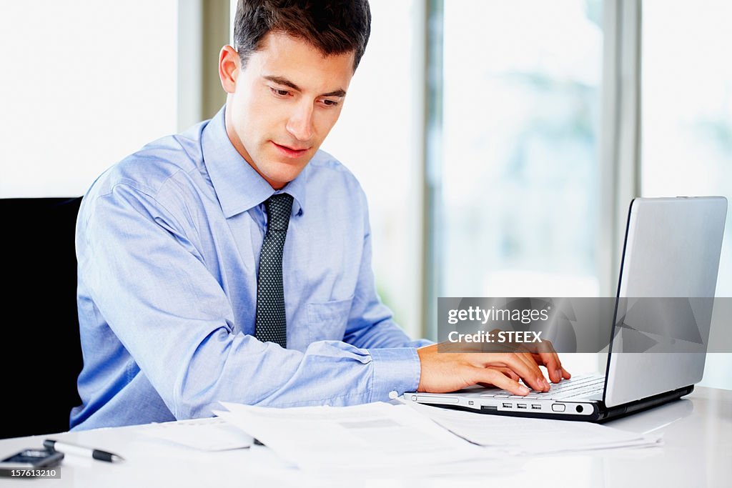 Busy businessman using a laptop at work