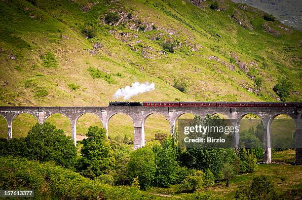 antique steam train running on a viaduct - glenfinnan viaduct stockfoto's en -beelden