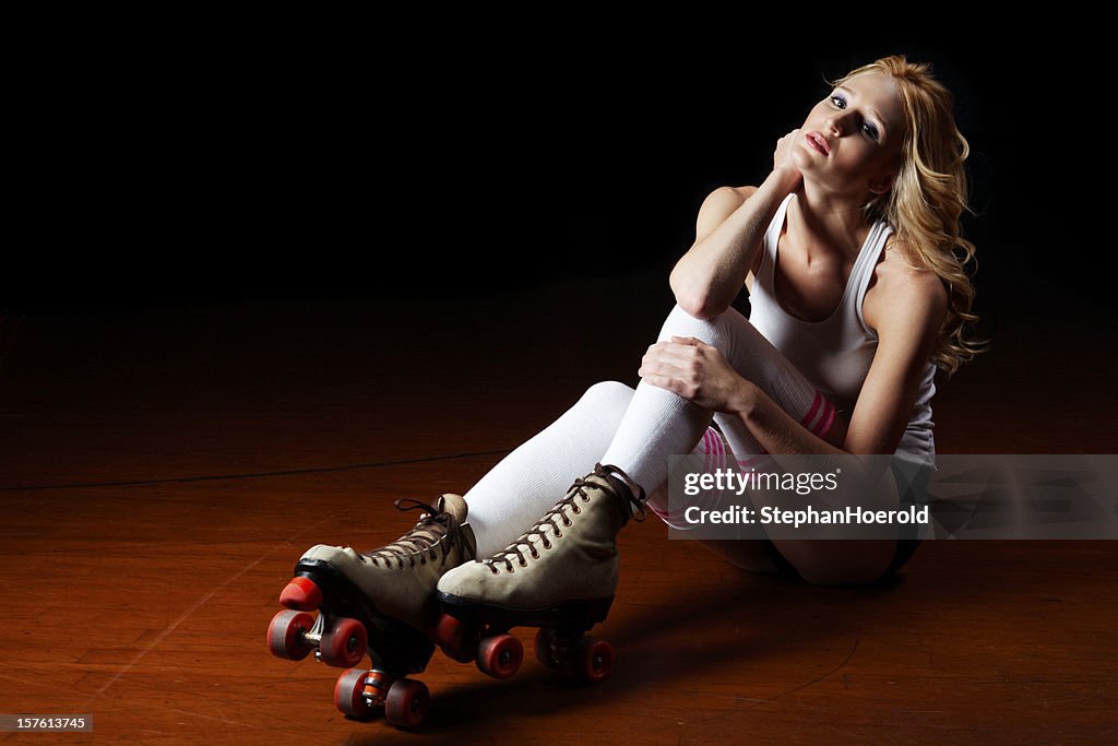 Portrait of roller skating girl sitting on rink