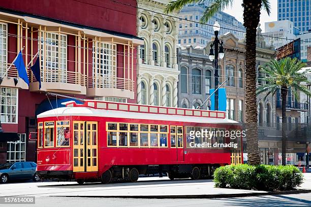 new orleans bright red streetcar traveling amid palms and flags - new orleans stock pictures, royalty-free photos & images