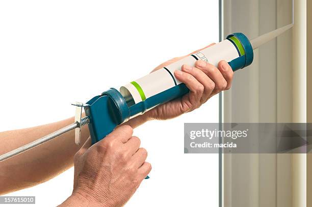 a handyman applying silicon on the corner of a wall - caulking stockfoto's en -beelden