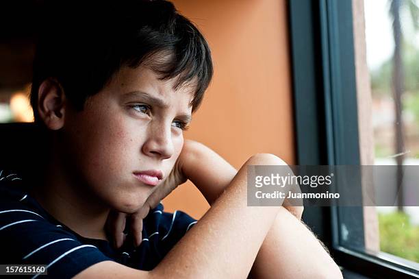 pensive child looking through a window - orphan boy stock pictures, royalty-free photos & images