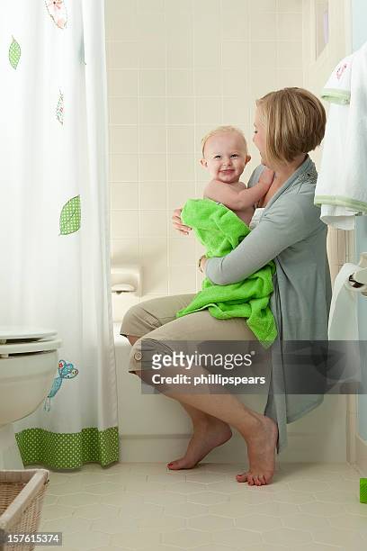 mother embracing toddler from bathtub. - kid bath mother stockfoto's en -beelden