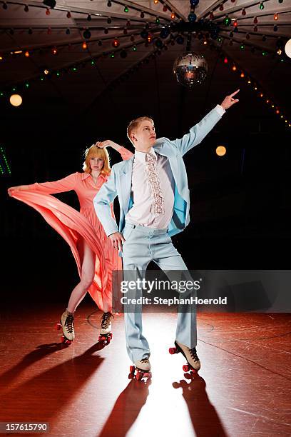 young couple roller skating, 70s style disco fever - rolschaatsen schaats stockfoto's en -beelden